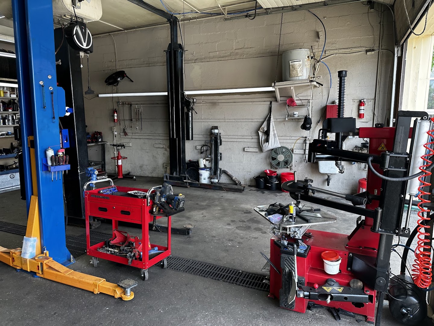 Auto service bay interior with hydraulic vehicle lift, tire changer, and wheel balancing equipment